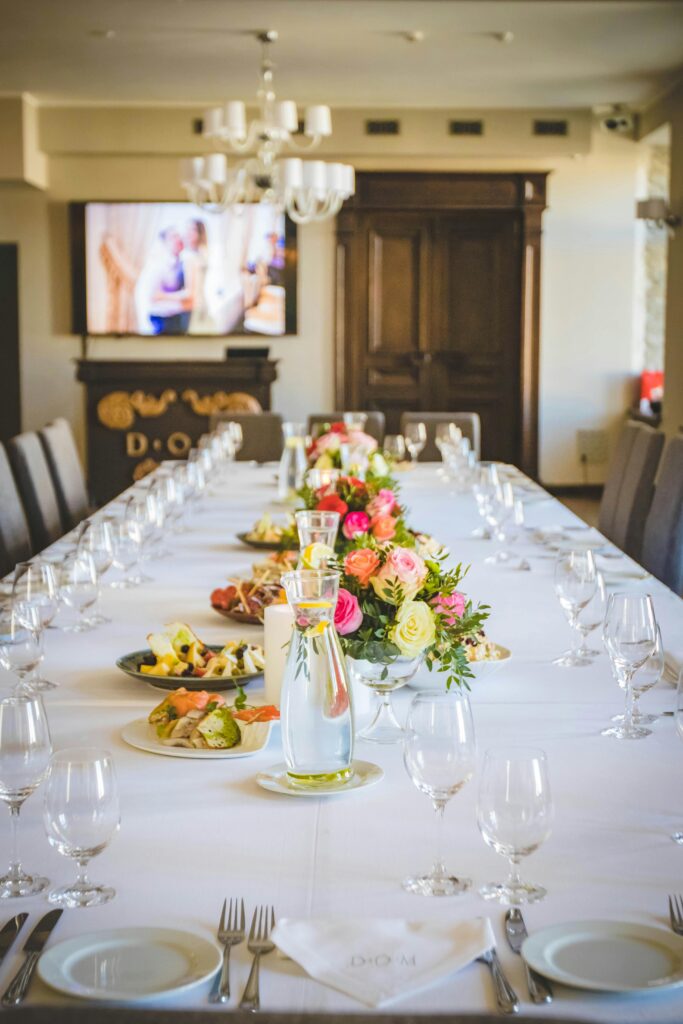 Long elegant dining table with a floral centerpiece and tableware set for a formal meal.