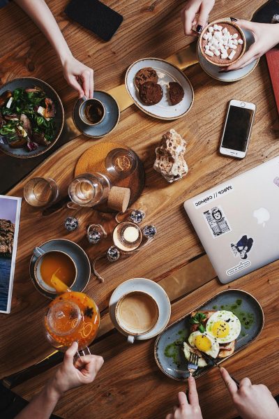 A group enjoying a diverse brunch spread with coffee on a rustic wooden table. Perfect for food and lifestyle themes.